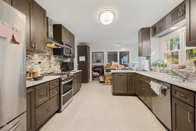 kitchen featuring a sink, light countertops, stainless steel appliances, and wall chimney exhaust hood