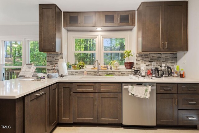 kitchen with dark brown cabinetry, a sink, light countertops, decorative backsplash, and stainless steel dishwasher