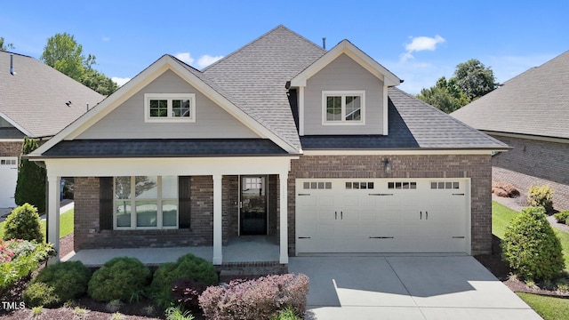 craftsman-style home with roof with shingles, a porch, driveway, and brick siding