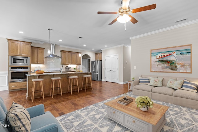 living area featuring ceiling fan, visible vents, crown molding, arched walkways, and recessed lighting