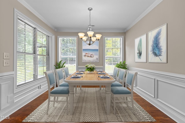 dining area featuring an inviting chandelier, ornamental molding, wainscoting, and dark wood-type flooring
