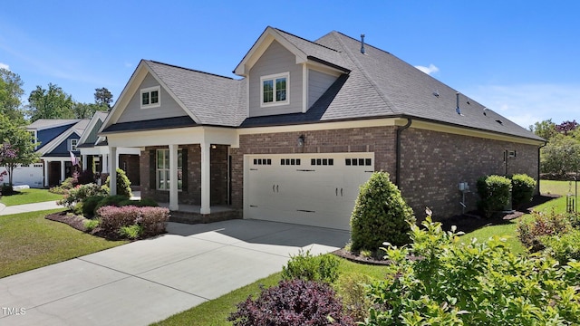 craftsman-style house with brick siding, a porch, a front yard, and concrete driveway