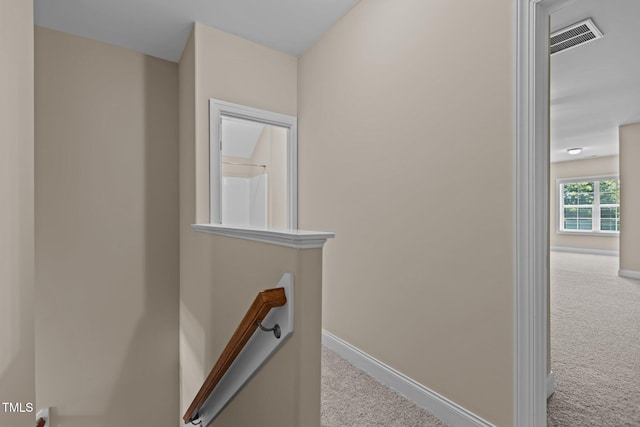 hallway with visible vents, carpet, baseboards, and an upstairs landing