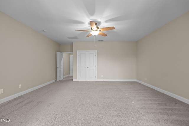 carpeted empty room featuring visible vents, a ceiling fan, and baseboards