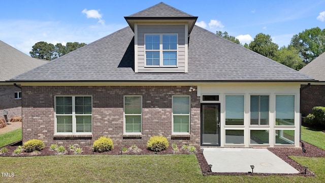 back of property with roof with shingles, a yard, a patio area, and brick siding