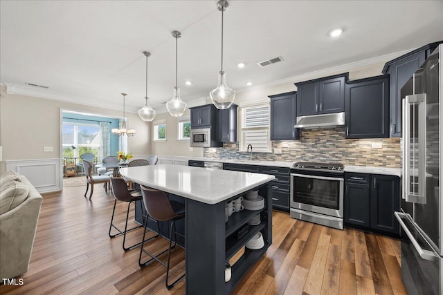 1533 Santa Lucia St, Wake Forest, NC 27587 - kitchen featuring stainless steel appliances, under cabinet range hood, light countertops, a sink, and a kitchen breakfast bar