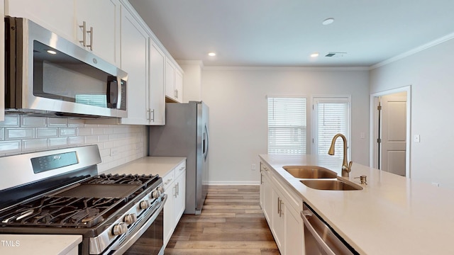 1314 Rosepine Dr, Cary, NC 27519 - kitchen with stainless steel appliances, a sink, light wood-style flooring, crown molding, and white cabinetry