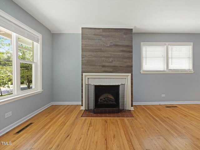 unfurnished living room with baseboards, a fireplace, visible vents, and wood finished floors