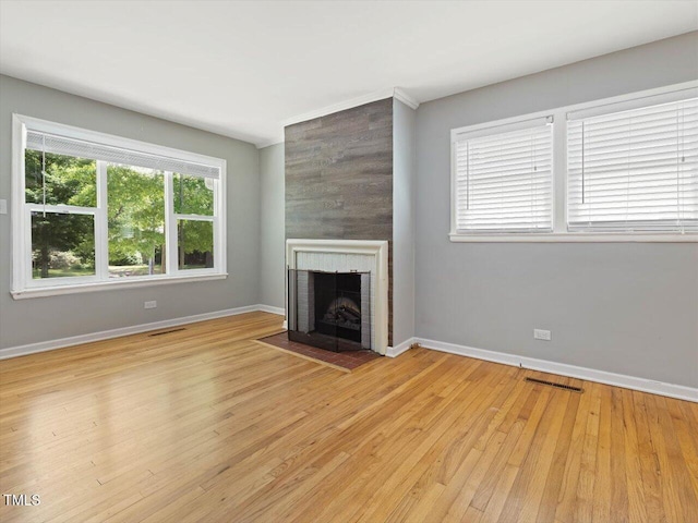 unfurnished living room featuring baseboards, a fireplace, light wood-style flooring, and visible vents