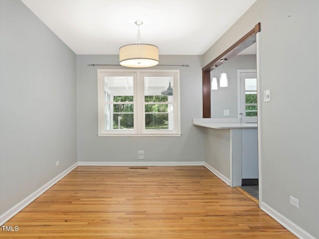 unfurnished dining area with visible vents, light wood-style flooring, and baseboards