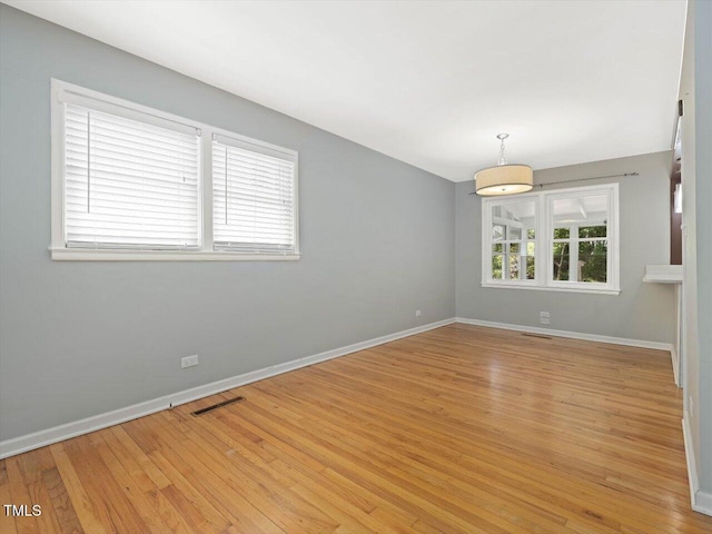 unfurnished room featuring light wood finished floors, baseboards, and visible vents