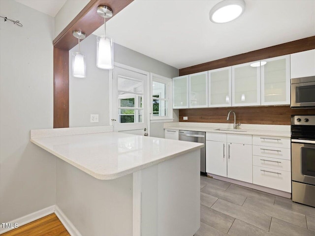 kitchen featuring light countertops, white cabinets, appliances with stainless steel finishes, and a sink