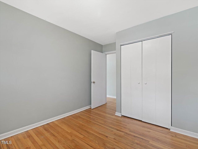 unfurnished bedroom with baseboards, a closet, and wood finished floors