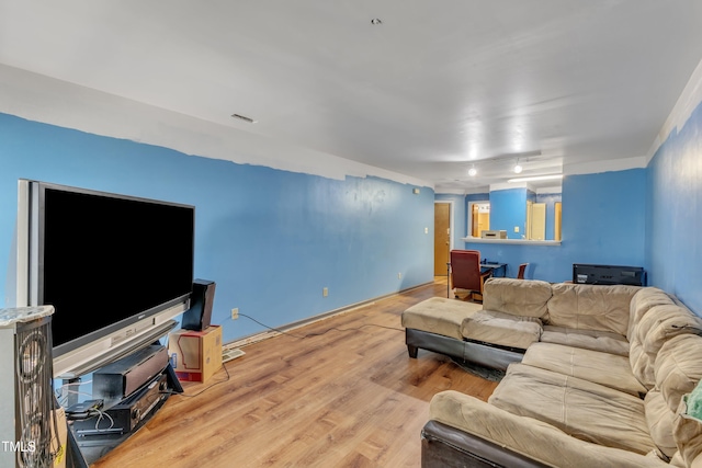 living room featuring baseboards, visible vents, and wood finished floors