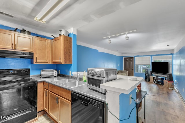 kitchen with under cabinet range hood, visible vents, a sink, open floor plan, and black appliances