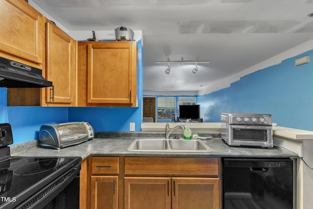 kitchen with brown cabinets, a sink, rail lighting, black appliances, and under cabinet range hood