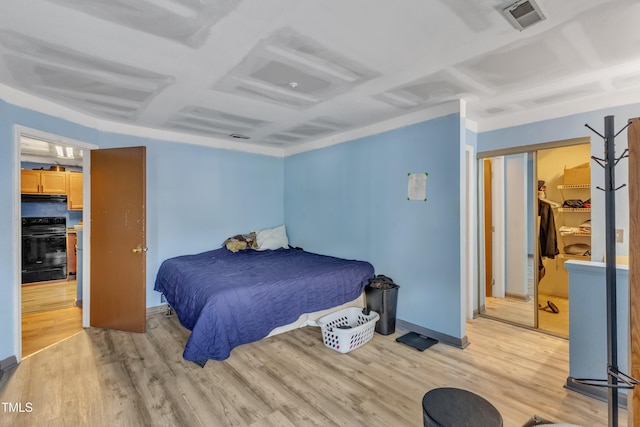 bedroom featuring light wood-style floors, visible vents, and baseboards