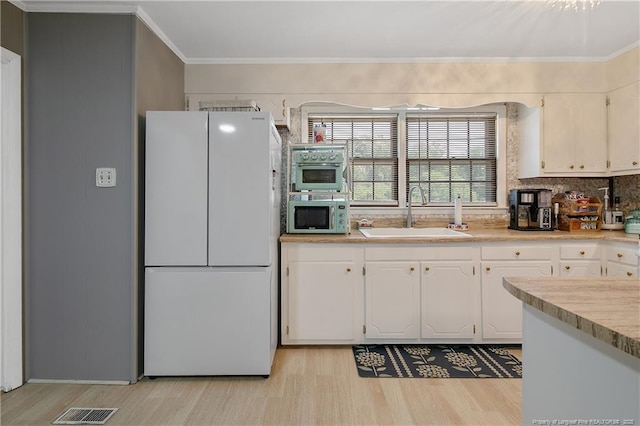 1810 Ashton Rd, Fayetteville, NC 28304 - kitchen with a sink, light wood finished floors, freestanding refrigerator, white cabinetry, and stainless steel microwave
