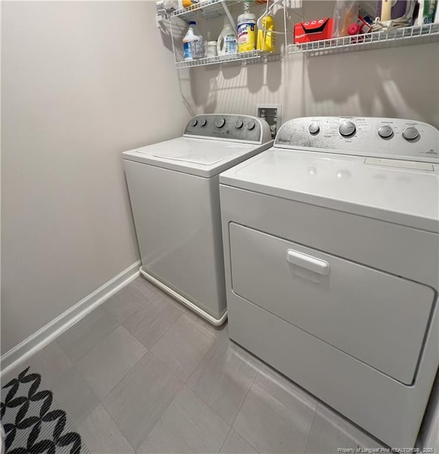 clothes washing area featuring baseboards, laundry area, and washing machine and dryer
