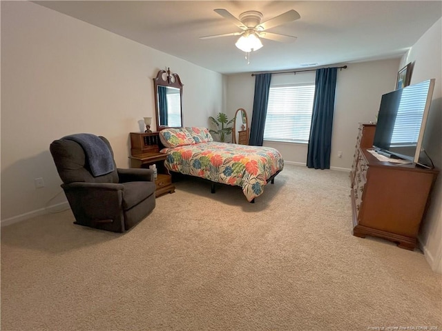 bedroom featuring light colored carpet, baseboards, ceiling fan, and multiple windows