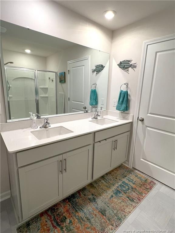 full bath featuring a sink, a shower stall, and double vanity
