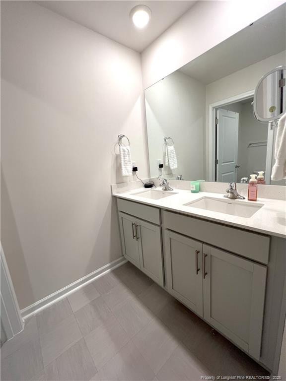 bathroom featuring a sink, baseboards, and double vanity