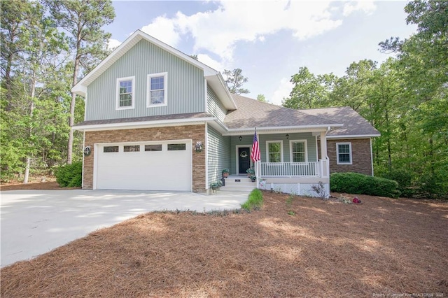 view of front of home featuring covered porch, concrete driveway, stone siding, and a garage