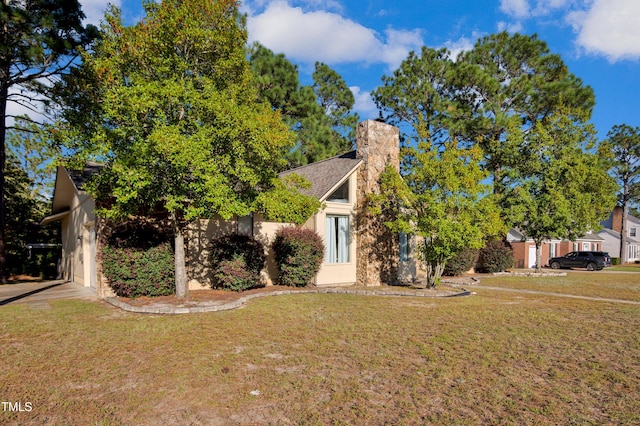 view of property hidden behind natural elements featuring a chimney, stucco siding, and a front yard