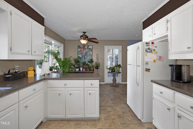 kitchen featuring freestanding refrigerator, a ceiling fan, white cabinetry, and a peninsula