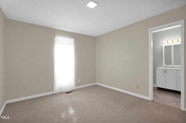 unfurnished bedroom with visible vents, a sink, carpet, and baseboards