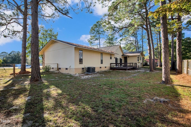 rear view of property featuring crawl space, a wooden deck, central air condition unit, fence, and a yard