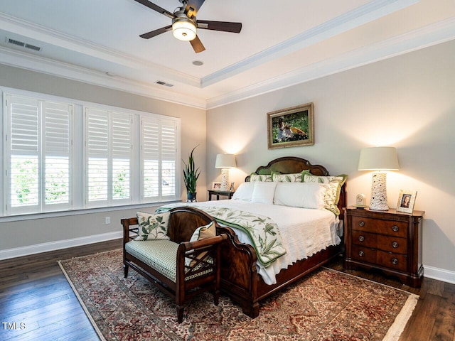 bedroom featuring wood finished floors, crown molding, baseboards, a tray ceiling, and a ceiling fan