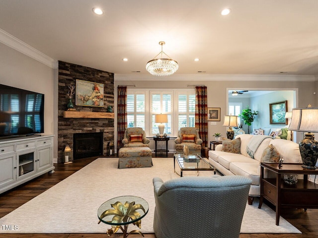 living room featuring ornamental molding, plenty of natural light, a stone fireplace, dark wood finished floors, and recessed lighting