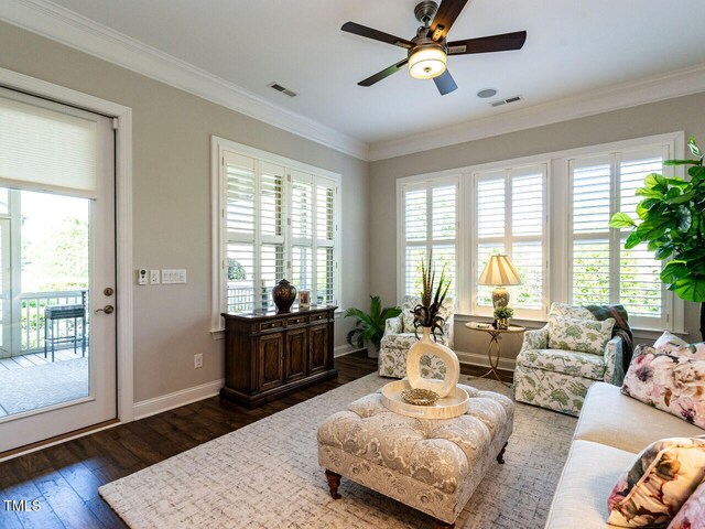 living area with dark wood finished floors, ornamental molding, ceiling fan, and baseboards