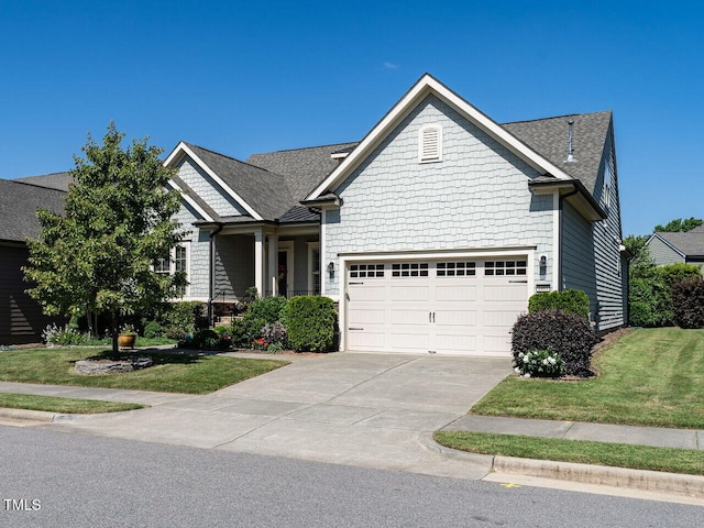 craftsman house with concrete driveway, a front lawn, and roof with shingles