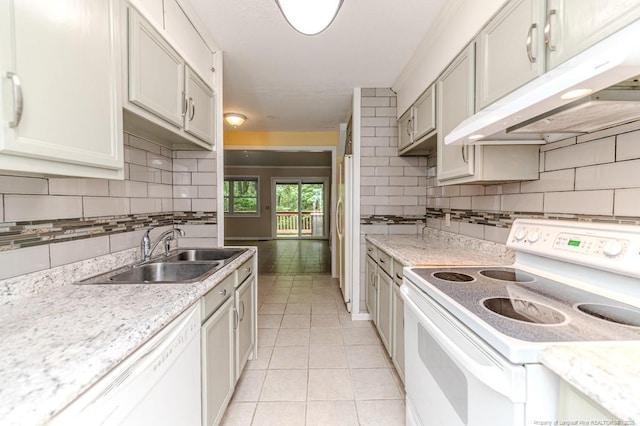 kitchen with white appliances, under cabinet range hood, tasteful backsplash, a sink, and light tile patterned floors
