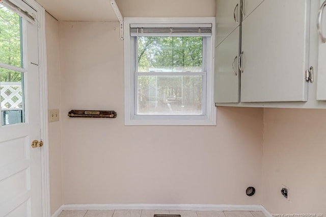 clothes washing area with cabinet space, light tile patterned floors, baseboards, and electric dryer hookup