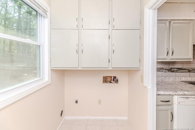 laundry area with baseboards and light tile patterned floors