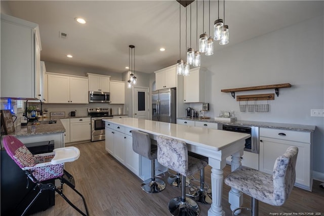 kitchen featuring a kitchen island, dark wood finished floors, white cabinets, stainless steel appliances, and recessed lighting