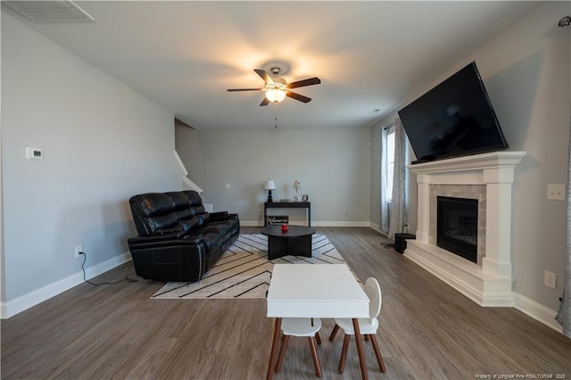 living area featuring visible vents, wood finished floors, a fireplace, baseboards, and ceiling fan