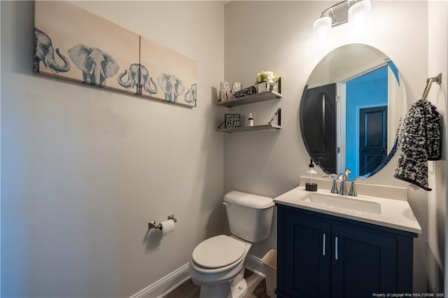 bathroom with toilet, baseboards, wood finished floors, and vanity