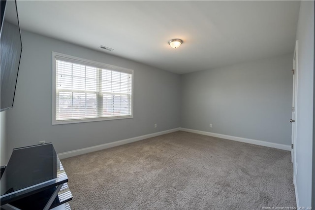 spare room with carpet floors, baseboards, and visible vents