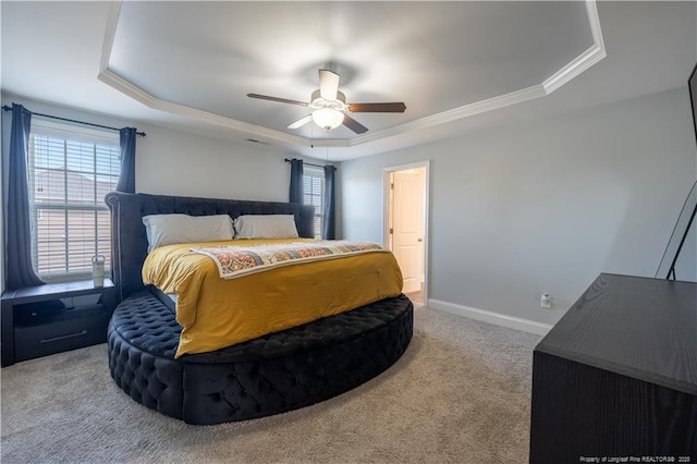 carpeted bedroom with crown molding, a tray ceiling, baseboards, and ceiling fan
