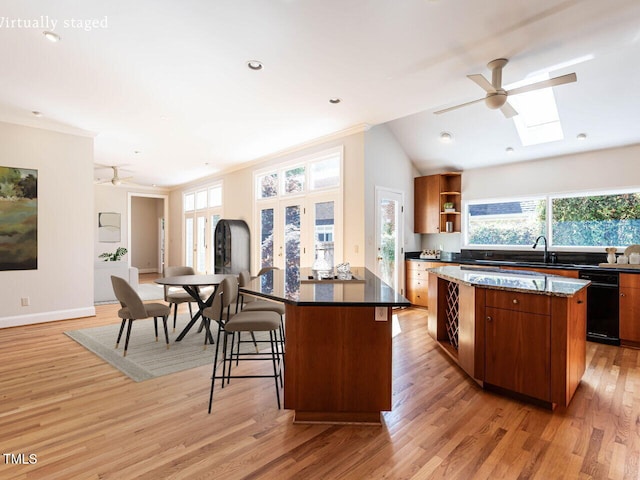 1605 Park Dr, Raleigh, NC 27605 - kitchen with a kitchen island, ceiling fan, black dishwasher, a kitchen breakfast bar, and light wood-style flooring