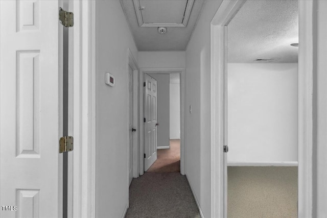 hall featuring visible vents, carpet flooring, and a textured ceiling