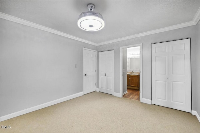 unfurnished bedroom with crown molding, baseboards, a textured ceiling, connected bathroom, and carpet flooring