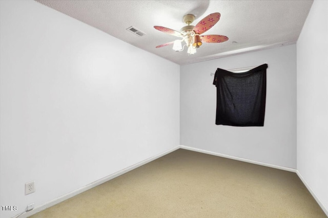carpeted empty room featuring visible vents, a ceiling fan, and baseboards