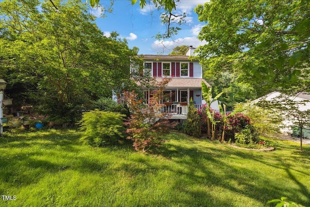 view of front of home with a chimney, a porch, and a front yard