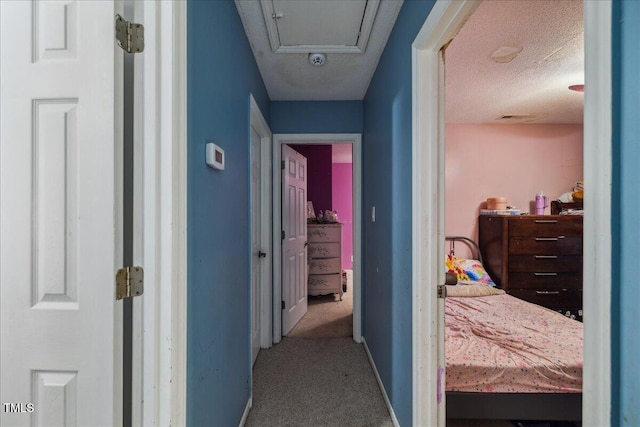 corridor featuring a textured ceiling, visible vents, baseboards, and carpet