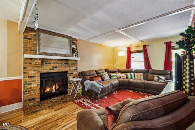 living area with a brick fireplace, a textured ceiling, and wood finished floors